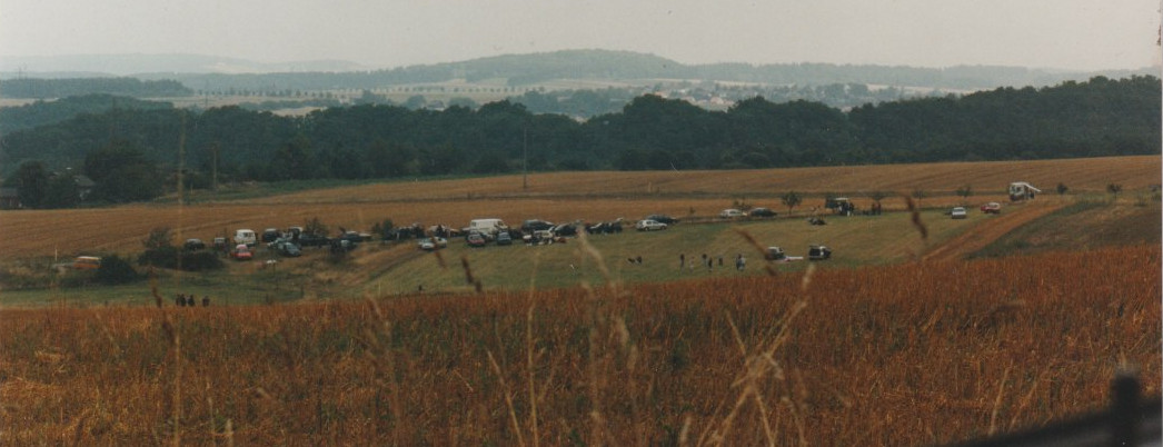 Ein Feld mit ein paar Dutzend Autos und Menschen.